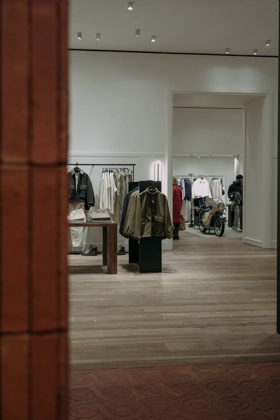 Kıyafet sergileri ve vintage bir motosikletin bulunduğu modern butik.